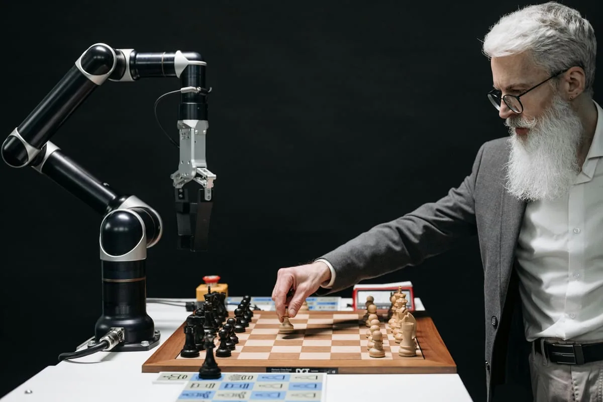 Homme âgé jouant aux échecs contre un bras robotisé