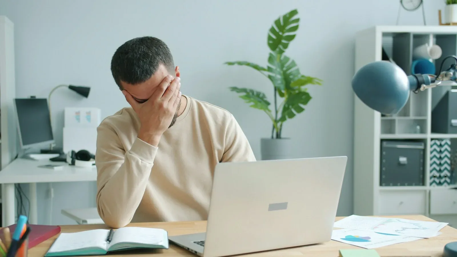 Un homme fatigué se frotte le visage devant son ordinateur portable